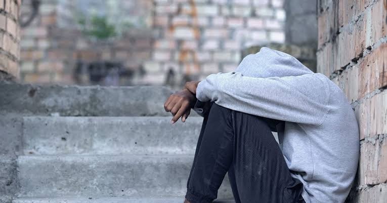Person seated on steps in an unfinished urban setting